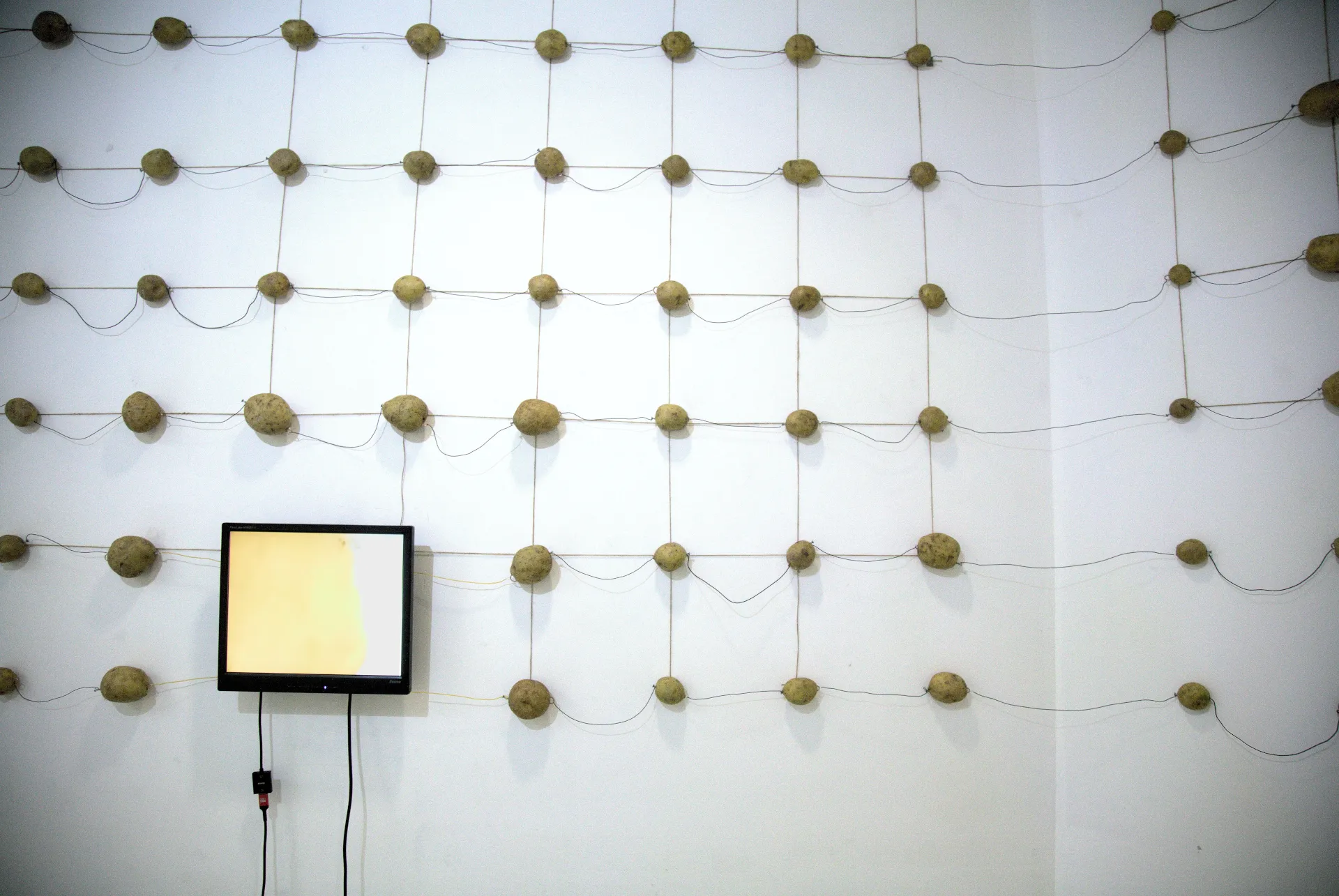 Monitor embedded in the potato wall generating an image of a potato, i potato self-portrait (2026) by Nikos Antonio Kourous Vázquez